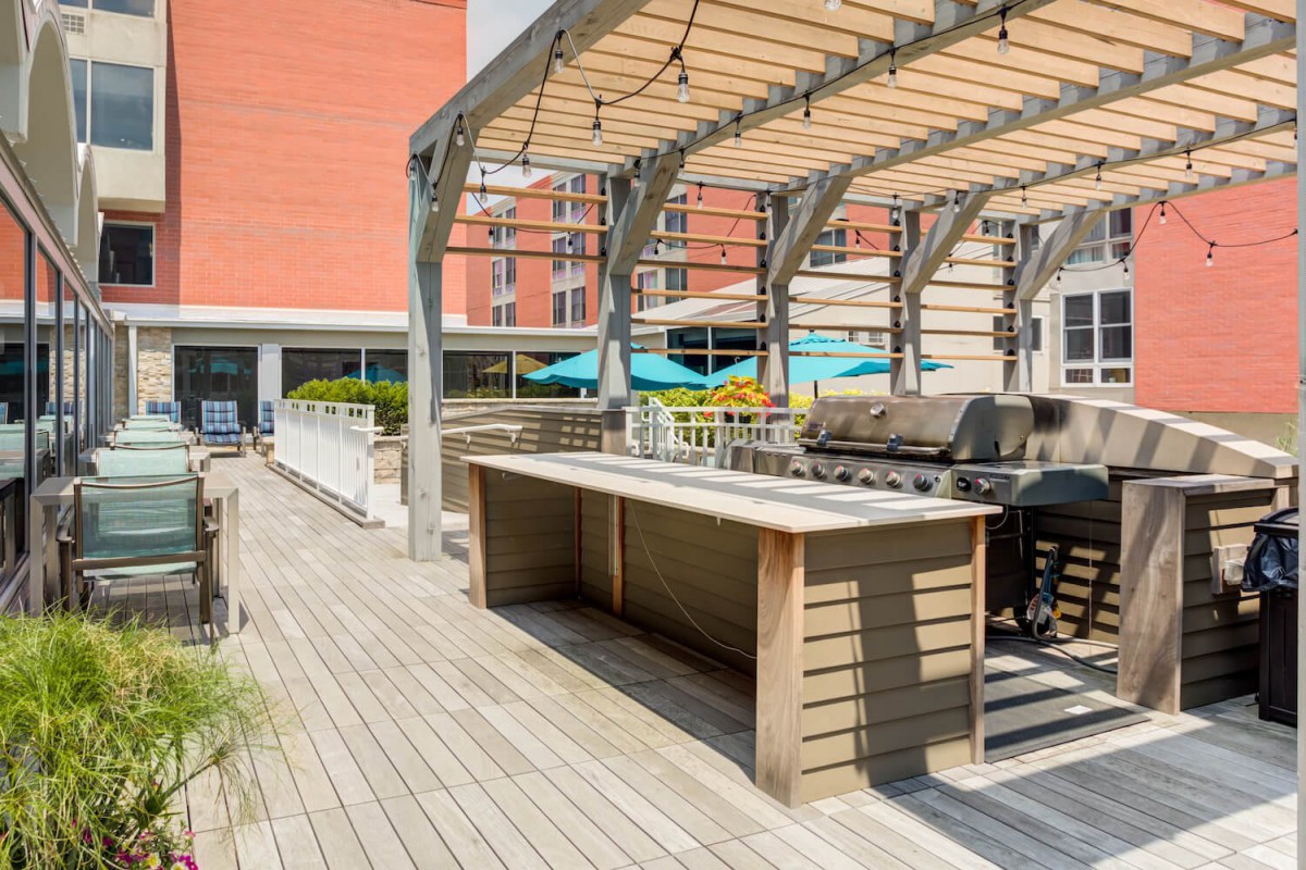 An outdoor deck with a pergola and grill area in an urban setting.