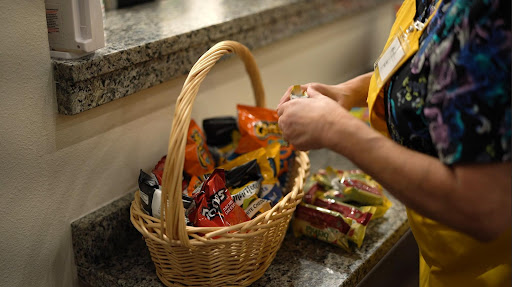 A person is selecting snacks from a woven basket on a granite countertop.
