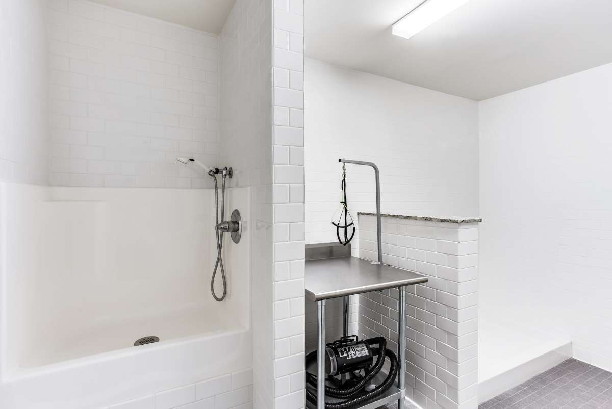 A minimalist bathroom featuring a bathtub with a shower and a stainless steel sink area.
