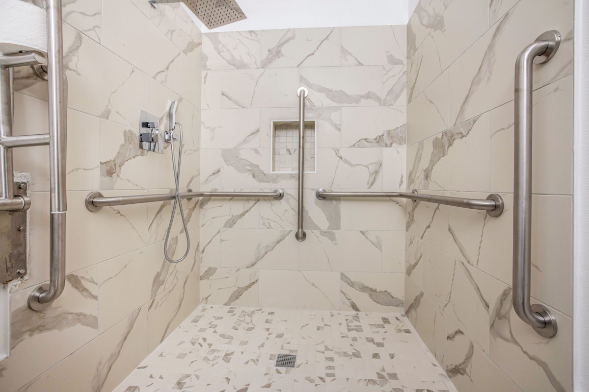 Modern bathroom shower with marble walls and accessible features.