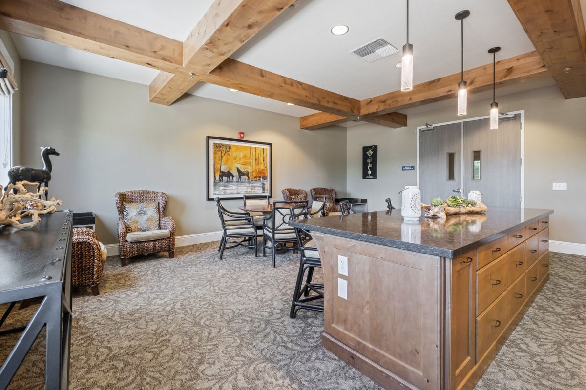A cozy living space with wooden beams, a kitchen island, and comfortable seating.