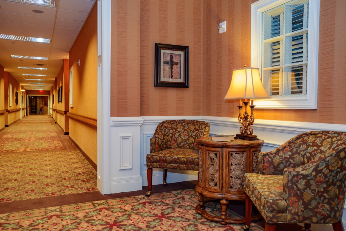 A warmly decorated hallway with chairs, a table, and a lamp.