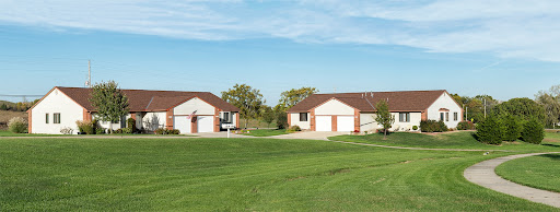 A peaceful suburban setting featuring two houses with a lush green lawn and blue sky.
