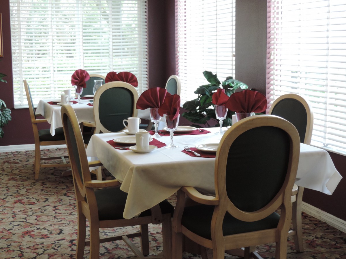An elegantly set dining room with tables adorned with red napkins and glasses.
