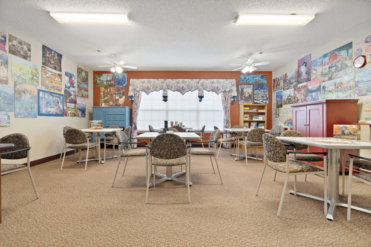 An empty classroom with tables and chairs, decorated with educational posters.