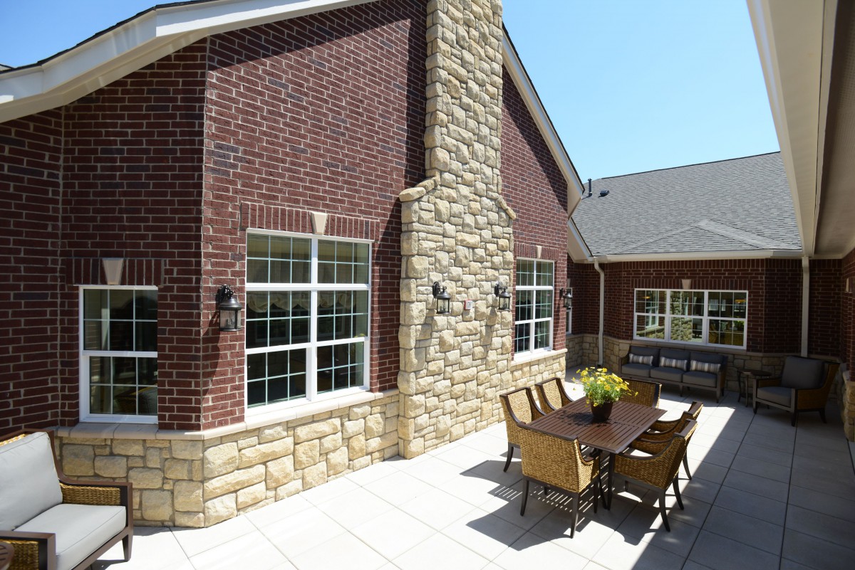 A sunny outdoor patio with a brick and stone facade, featuring patio furniture.