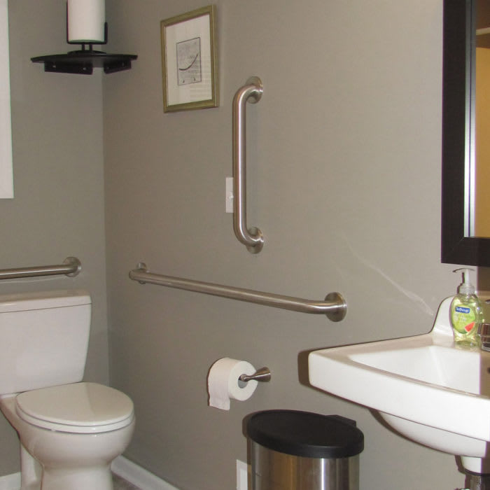 A bathroom with accessibility features, including grab bars next to the toilet and sink.