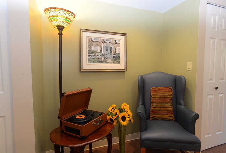 A cozy living room corner with a vinyl record player, armchair, and sunflowers.