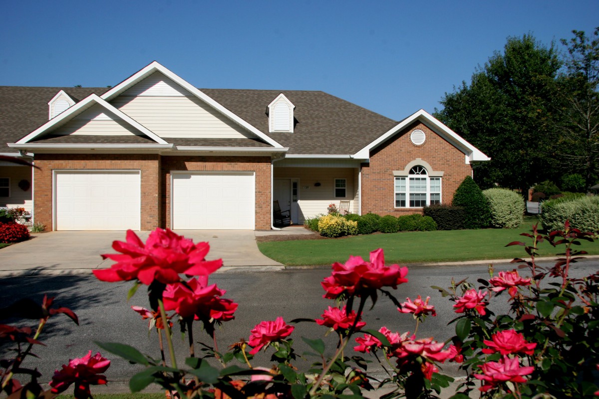 A suburban house with a beautifully landscaped garden featuring blooming red roses.