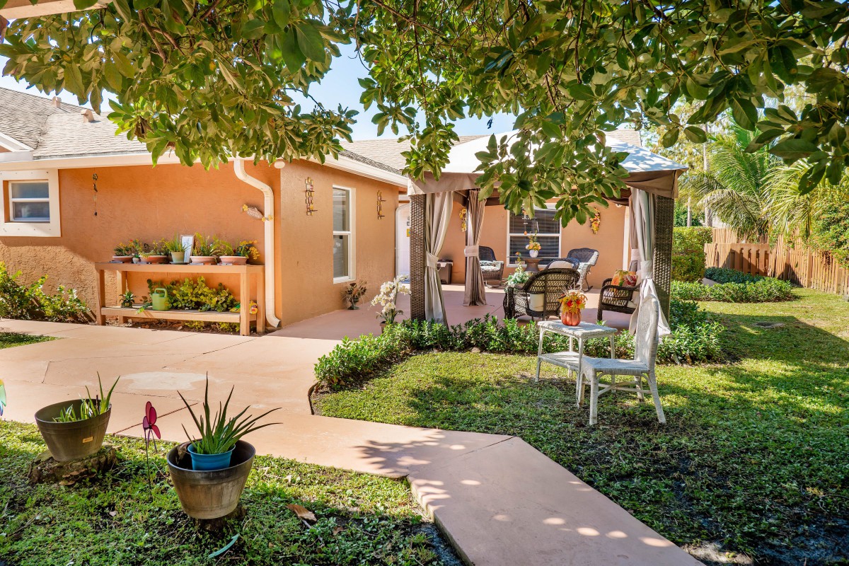 A cozy backyard with a patio, lush greenery, and comfortable outdoor seating.