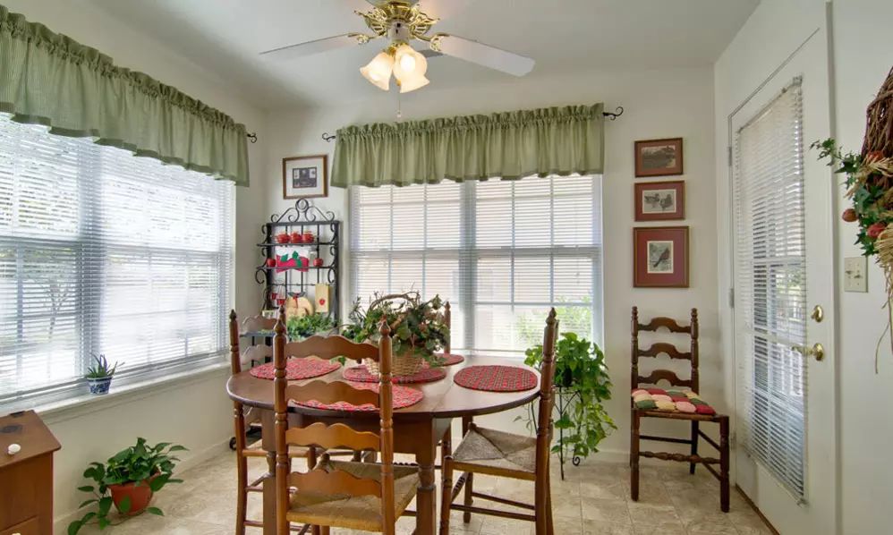 A cozy dining room with a wooden table and chairs, decorated with plants and wall art.