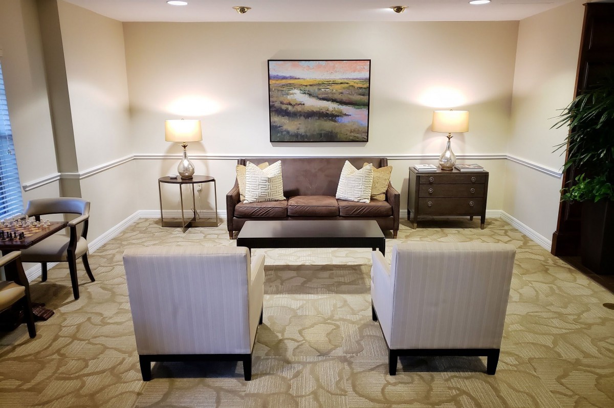 A modern living room with a sofa, two chairs, and stylish lamps, featuring artwork on the wall.