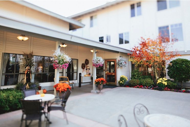 A charming courtyard with hanging flower baskets and patio furniture, set against a warm autumn backdrop.