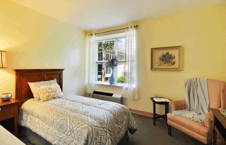 A cozy bedroom with a large window and simple decor.