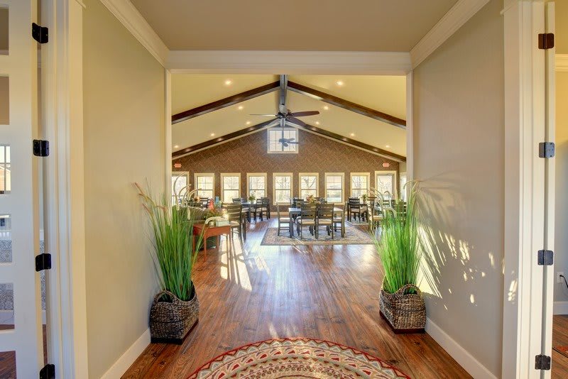 A spacious living room with vaulted ceilings, wooden floors, and plenty of natural light.