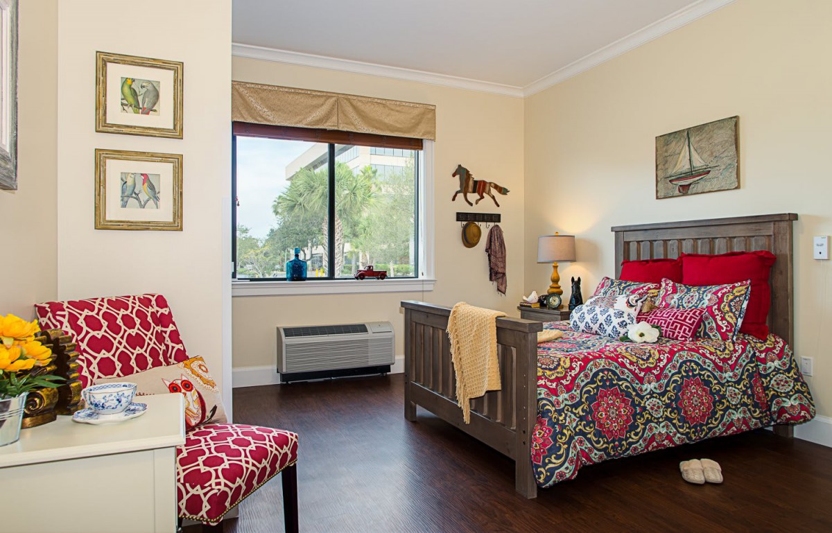 A cozy bedroom with a vibrant bedspread and decorative accents, featuring a window view.