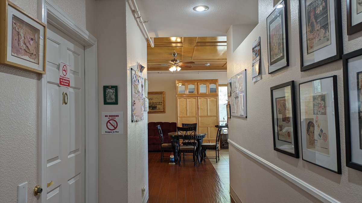 A cozy hallway leading to a dining area with wooden floors and a ceiling fan.