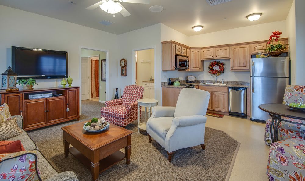 A cozy living room with comfortable armchairs and a coffee table, adjacent to a kitchen area in a modern home.