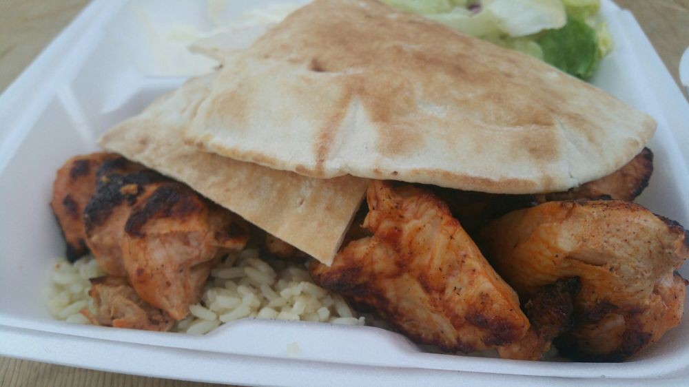 A dish featuring grilled chicken, pita bread, and rice.
