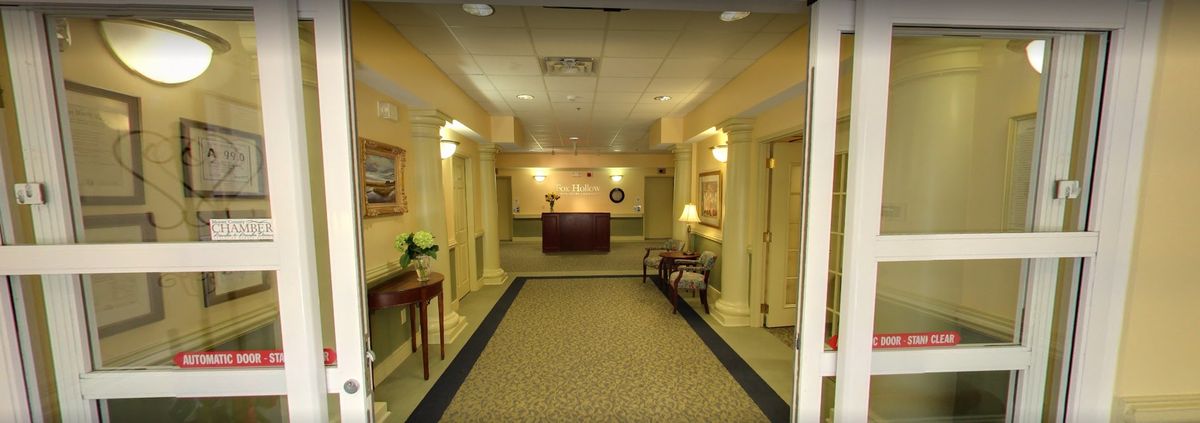 A well-lit lobby area featuring a reception desk, carpeted floor, and decorative elements such as paintings and lamps.