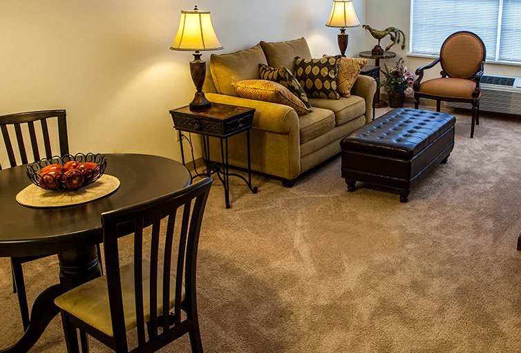 A cozy living room with a sofa, side tables, lamps, and a carpeted floor.