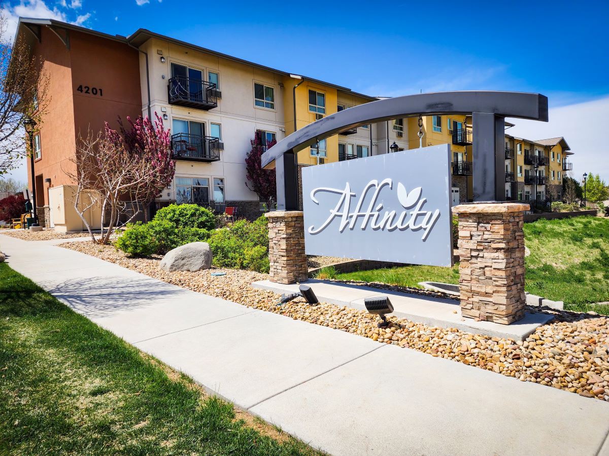 An apartment complex with a prominent entrance sign and well-maintained landscaping.