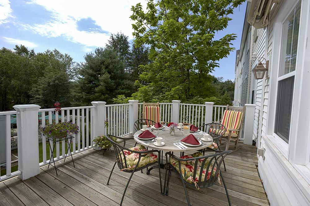 A sunny outdoor patio with a dining set surrounded by greenery.