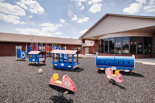 A vibrant playground designed for children, featuring colorful equipment and a spacious pavilion under a partly cloudy sky.