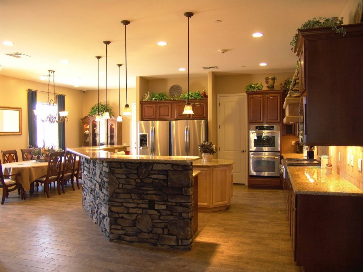 A modern kitchen featuring a stone island, pendant lighting, and stainless steel appliances.