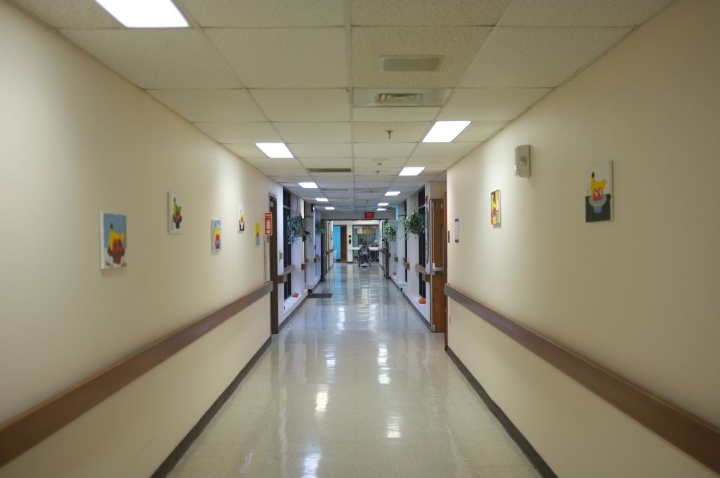 A long hospital hallway with bright lighting and artwork on the walls.