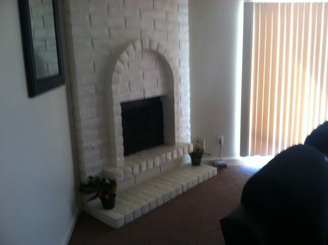 A cozy living room features a white brick fireplace.