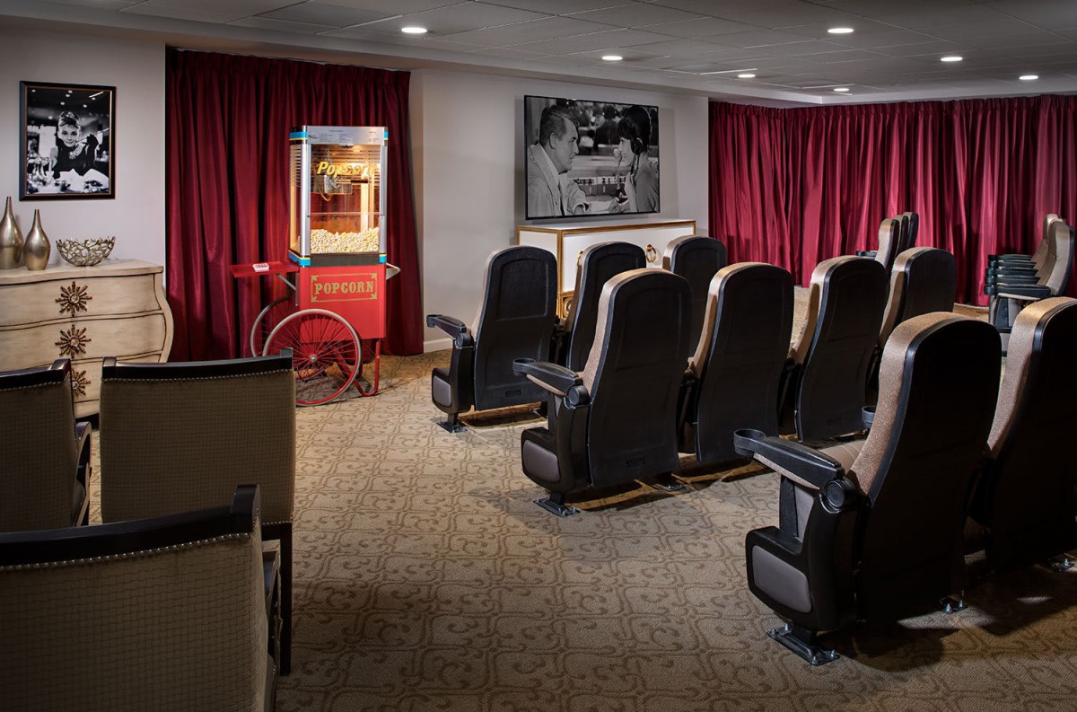 A cozy home theater setup featuring comfortable seating, a popcorn machine, and red curtains.