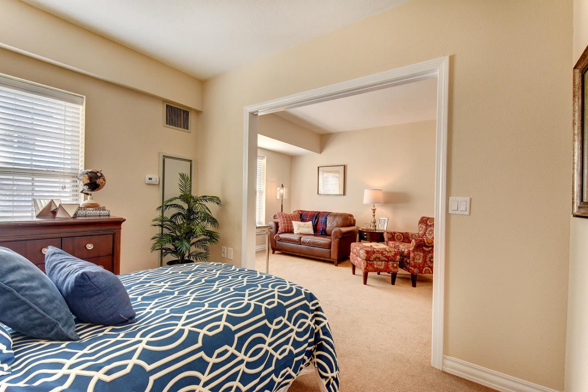 A cozy bedroom with a view into a warmly decorated living room.