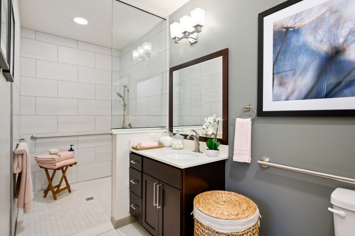 A modern bathroom with a vanity, mirror, and shower area.