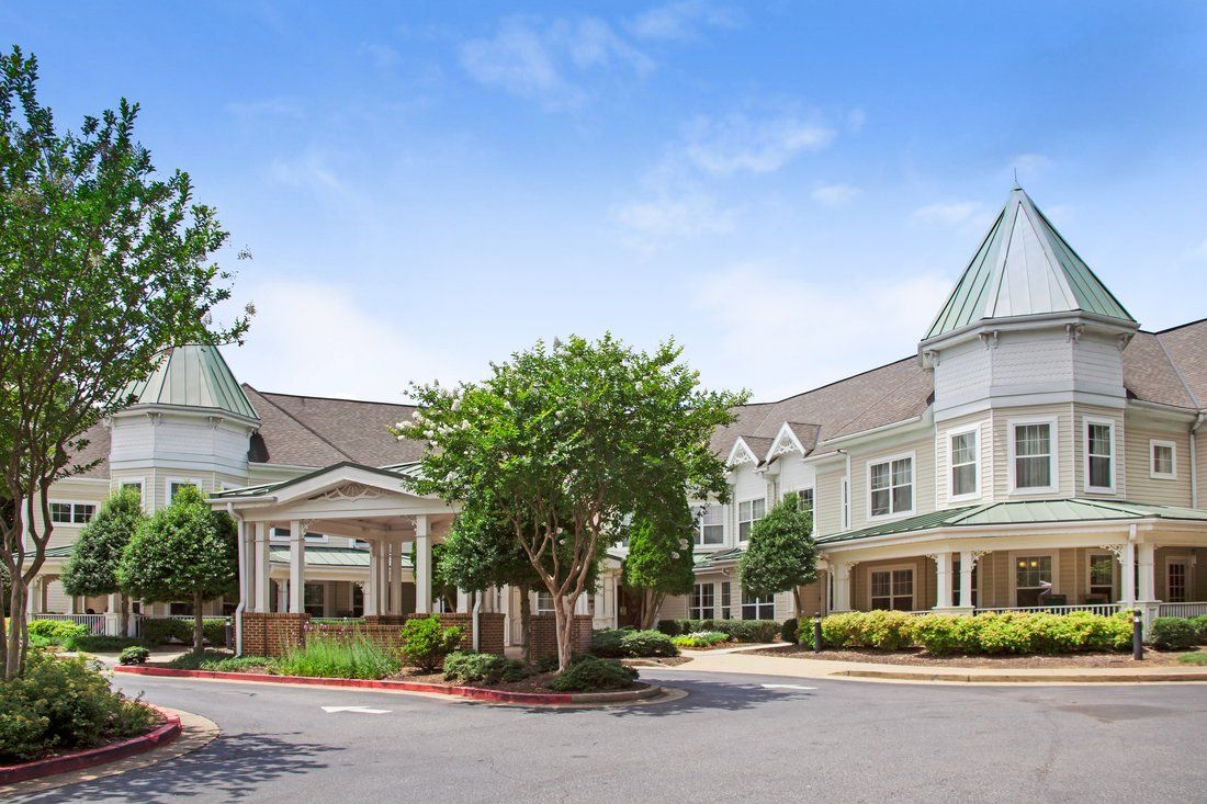 A large residential building with a landscaped entrance and clear blue sky.