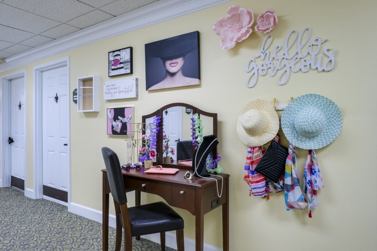 A stylish vanity area with a decorated wall featuring hats, artwork, and a mirror.
