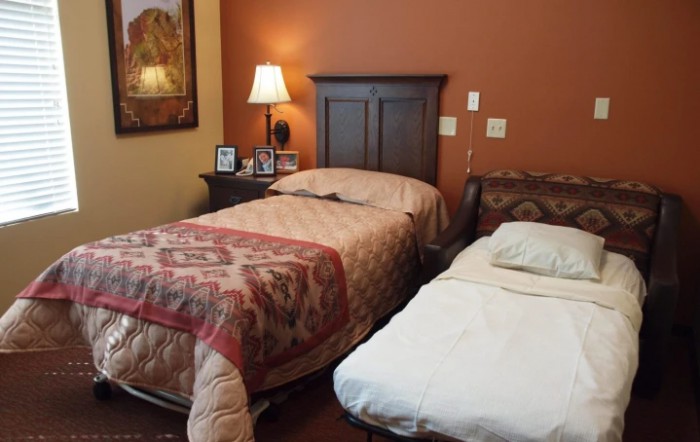 A cozy bedroom with two beds, a nightstand, and a lamp.