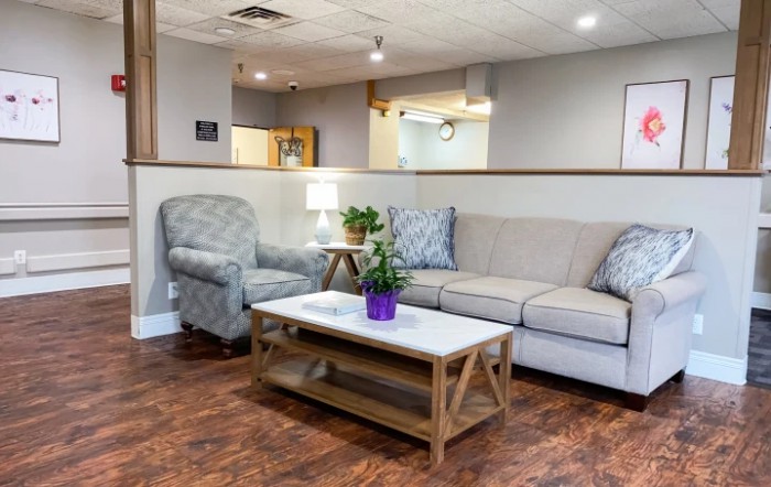 A cozy living room with a beige couch, armchair, and a coffee table featuring an indoor plant.