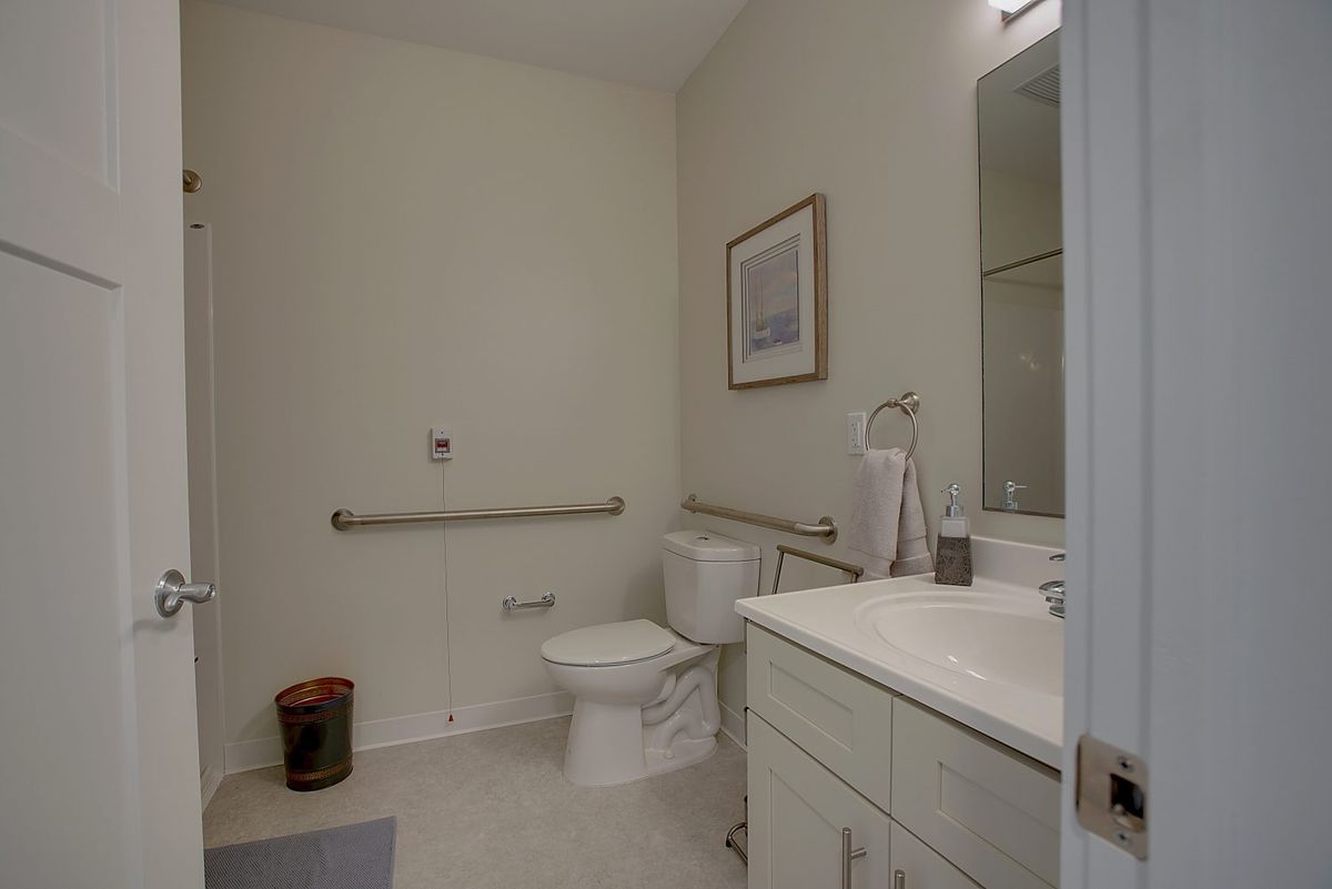 A modern bathroom with accessibility features, including grab bars near the toilet and a clean, minimalist design.