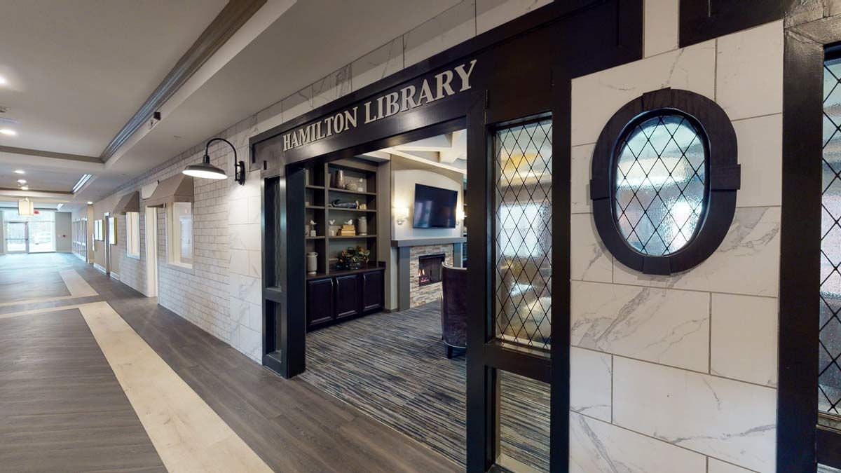 Entrance to a modern library with bookshelves and a fireplace.
