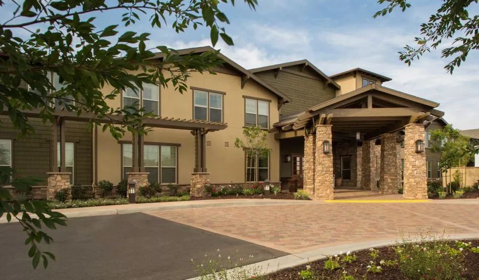 A two-story residential building with landscaped surroundings and a driveway.