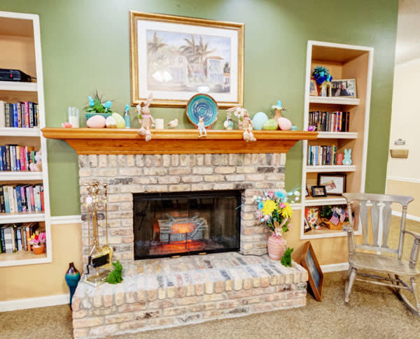 Cozy living room with a brick fireplace surrounded by decorative items and built-in shelves filled with books.