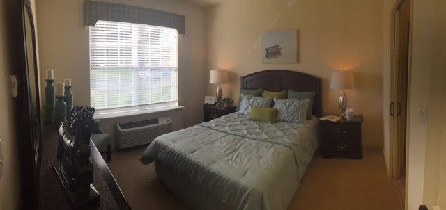 A neatly arranged bedroom with a made bed and bedside lamp.