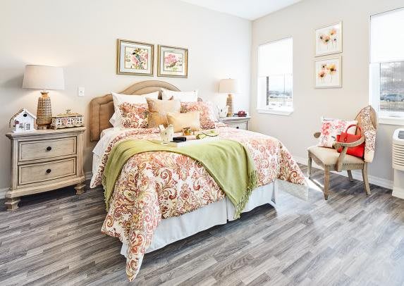 A bright and cozy bedroom with floral-patterned bedding and natural light streaming in.