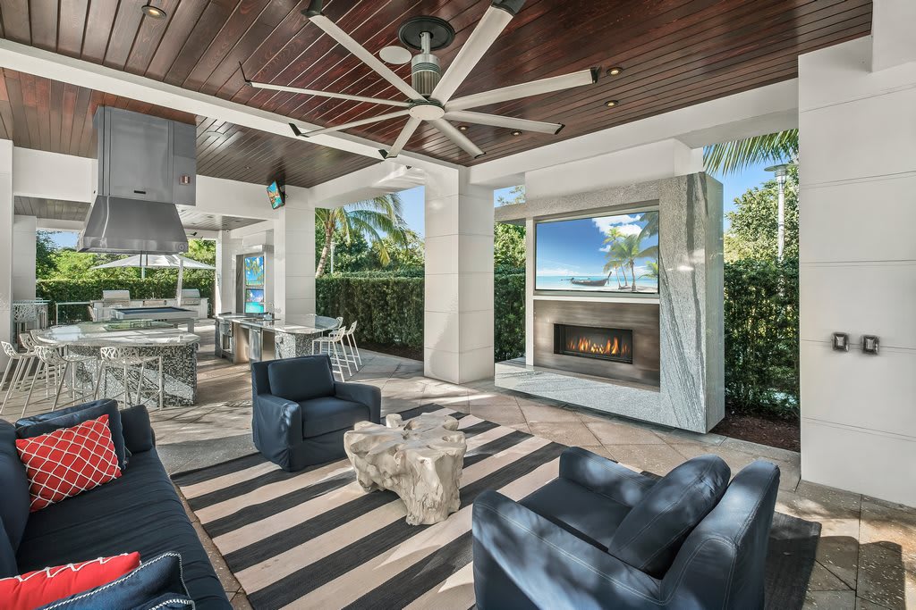A luxurious outdoor patio featuring comfortable seating, a fireplace, and modern decor.