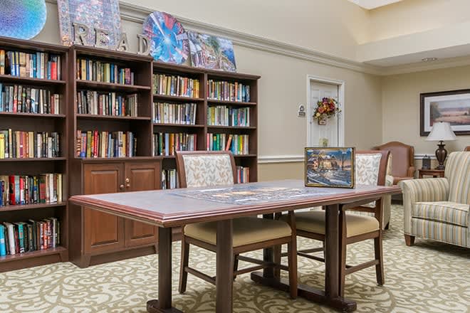 A cozy library nook with a table set for puzzling and bookshelves filled with a variety of books.