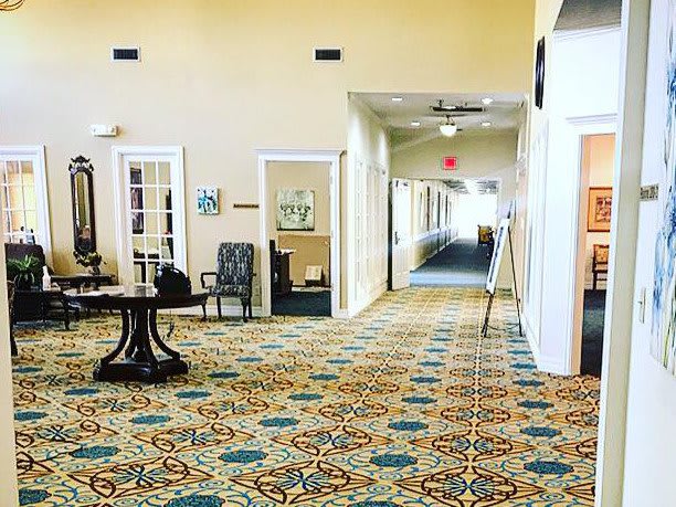 A spacious lobby with patterned carpet leading to a hallway.
