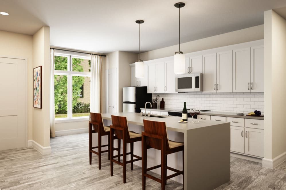 A modern kitchen featuring white cabinets, an island with bar stools, and elegant pendant lighting.