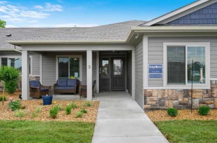 A modern residential house with a front porch and well-maintained lawn.