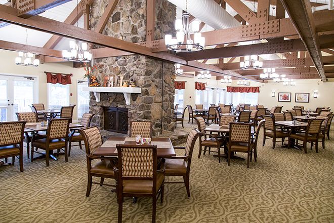 A cozy dining room with a stone fireplace and neatly arranged tables and chairs.